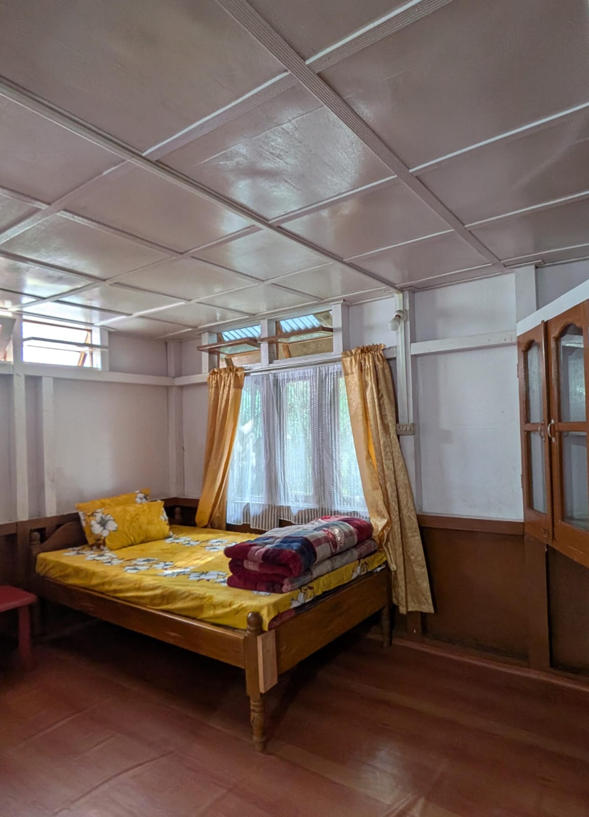 The yellow double bed in Room 4, by gold curtains and a glass cupboard